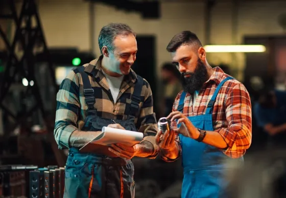 Sản phẩm two storage employees examining a metal piece doi — Gia Công Cơ Khí Chính Xác Minh Hoàng - Công Ty TNHH Công Nghệ Minh Hoàng — MST 0201741174