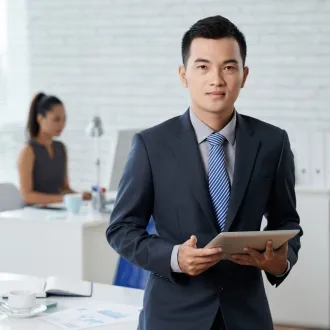 Sản phẩm waistup shot asian business man standing moddle office holding digital tablet 5300 — Kiên Long Hoàng - Công Ty TNHH Dịch Vụ Bảo Vệ Kiên Long Hoàng — MST 0312802249